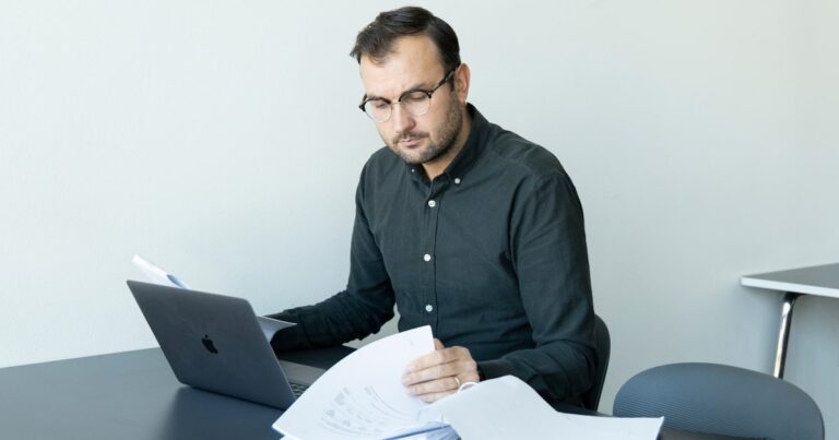 Hvorfor bruge et digitalt regnskabsprogram - en mand på et kontor og kigger på computer og dokumenter