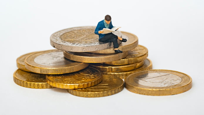 investering - billede af mandefigur ovenpå euromønter