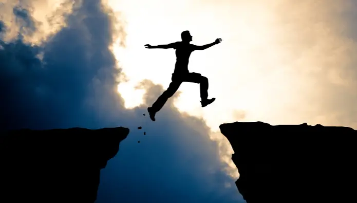 10 nytårsforsæt for iværksættere - en mand der hopper mellem to klippe